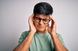© Krakenimages.com - Young handsome man wearing casual t-shirt and glasses over isolated white background suffering from headache desperate and stressed because pain and migraine. Hands on head.
