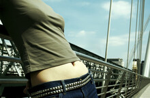 Close-up Picture Of A Woman Exposing Her Navel While Leaning On A Bridge