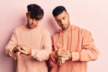 Poster - Young gay couple wearing casual clothes checking the time on wrist watch, relaxed and confident