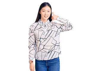 Sticker - Young beautiful chinese woman wearing casual shirt smiling doing phone gesture with hand and fingers like talking on the telephone. communicating concepts.