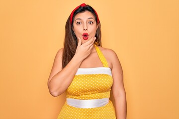 Canvas Print - Young hispanic pin up woman wearing fashion sexy 50s style over yellow background Looking fascinated with disbelief, surprise and amazed expression with hands on chin