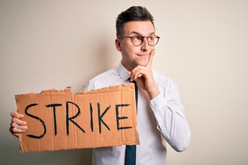 Wall Mural - Young handsome caucasian business man holding protest banner on job strike serious face thinking about question, very confused idea