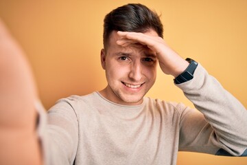 Poster - Young handsome caucasian man talking a selfie picture over yellow isolated background stressed with hand on head, shocked with shame and surprise face, angry and frustrated. Fear and upset for mistake