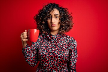 Sticker - Young beautiful curly arab woman drinking mug of coffee over isolated red background with a confident expression on smart face thinking serious