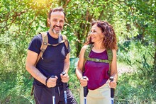 Beautiful Couple Of Hiker Wearing Backpack Smiling Happy. Standing With Smile On Face Doing Trekking Using Hiking Stick At Forest