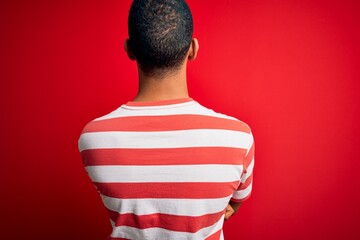 Wall Mural - Young handsome african american man wearing casual striped t-shirt and glasses standing backwards looking away with crossed arms