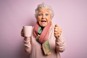 Wall Mural - Senior beautiful grey-haired woman drinking mug of coffee over isolated pink background screaming proud and celebrating victory and success very excited, cheering emotion