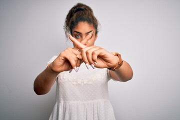 Poster - Young beautiful african american girl wearing casual t-shirt standing over white background Rejection expression crossing fingers doing negative sign