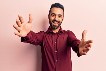 Young hispanic man wearing casual clothes looking at the camera smiling with open arms for hug. cheerful expression embracing happiness.