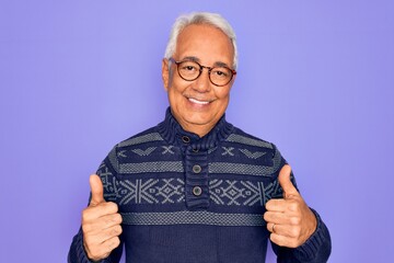 Poster - Middle age senior grey-haired man wearing glasses and winter sweater over purple background success sign doing positive gesture with hand, thumbs up smiling and happy. Cheerful expression.