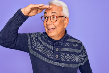 Canvas Print - Middle age senior grey-haired man wearing glasses and winter sweater over purple background very happy and smiling looking far away with hand over head. Searching concept.