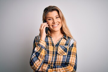 Wall Mural - Beautiful blonde woman having conversation talking on the smartphone over white background with a happy face standing and smiling with a confident smile showing teeth