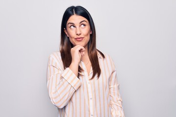 Sticker - Young beautiful brunette woman wearing casual striped shirt standing over white background thinking concentrated about doubt with finger on chin and looking up wondering