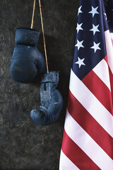 Old Boxing gloves hang on the wall next to the flag of the United States of America.