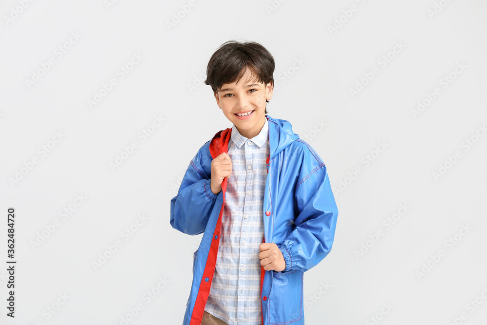 Cute little boy in raincoat on light background