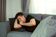 © wutzkoh - Asian people feel unhealthy while lying on the sofa at home while he have a cough due to bronchitis.