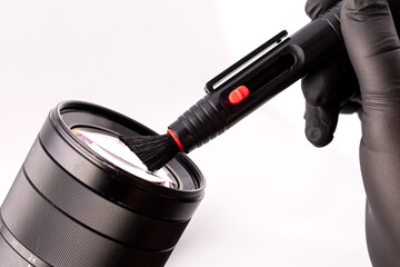 A girl photographer in gloves cleans the lens with special tools for cleaning professional optics.  Care for photo equipment.