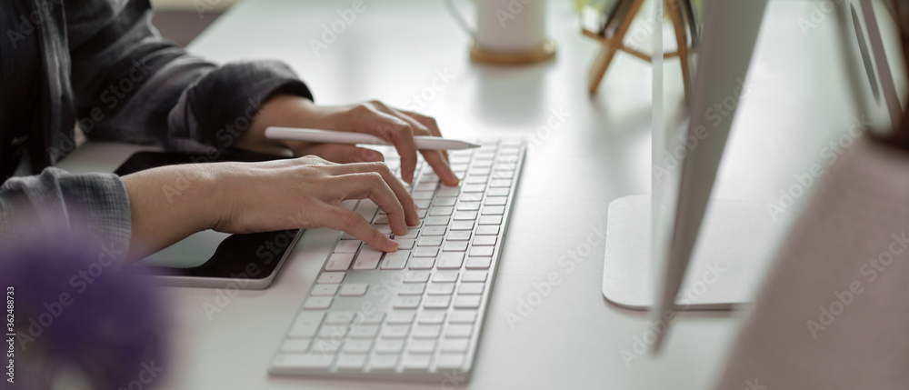 Female hands typing on computer keyboard while holding stylus pen on white office desk - obrazy, fototapety, plakaty 