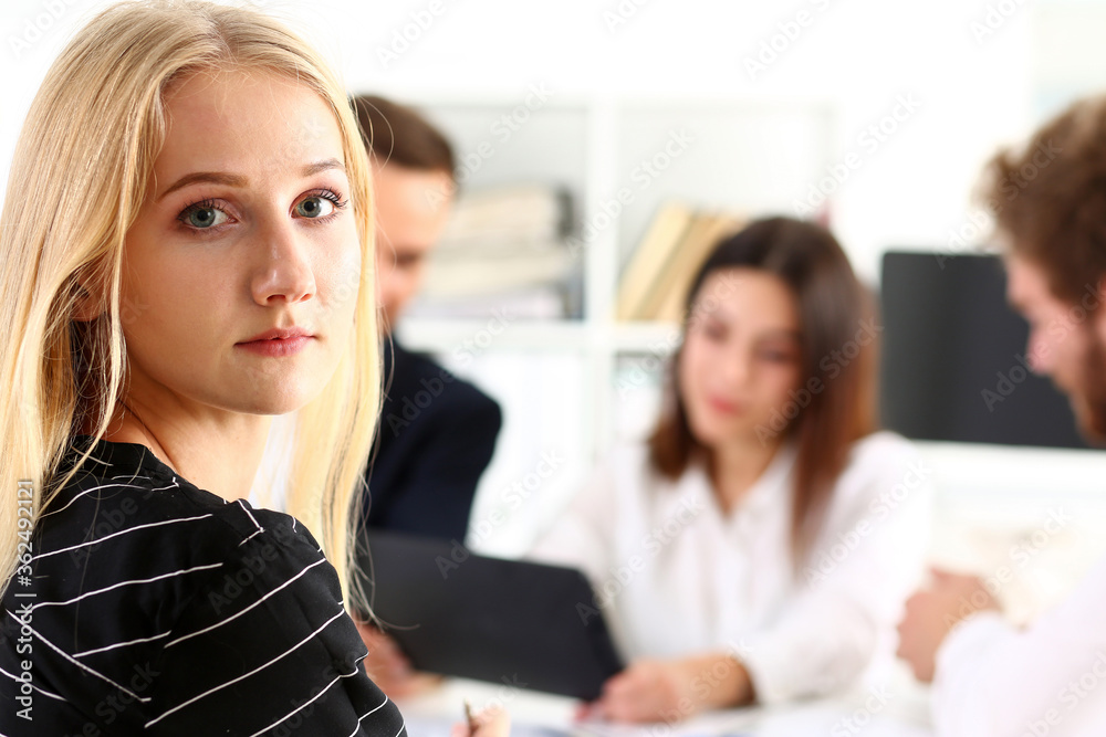 Beautiful smiling cheerful girl at workplace look in camera with colleagues group in background. White collar worker at workspace, job offer, modern lifestyle, client visit, profession train concept - obrazy, fototapety, plakaty 