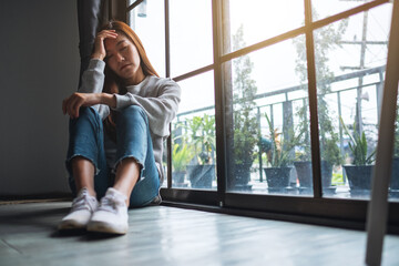 Wall Mural - A sad and stressed young asian woman sitting alone in the room