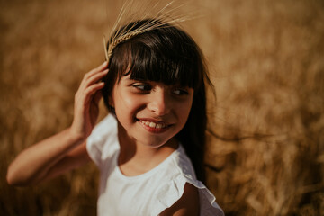 portrait of a girl having fun with an ear of wheat in a wheat field under a sunset