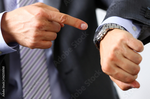 Cuadros en Lienzo Man in suit and tie check out time at silver wristwatch closeup