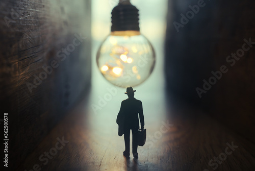 Fotografía Surreal image of person in dark corridor looking at glowing light bulb