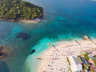 Wall Mural - Aerial view of a beautiful white sand beach with turquoise water and relaxing people on a sunny day. Ksamil, Albania.