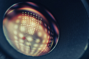 Poster - Beautiful Camera Lens on a dark with yellow shine reflection light background. Macro view.
