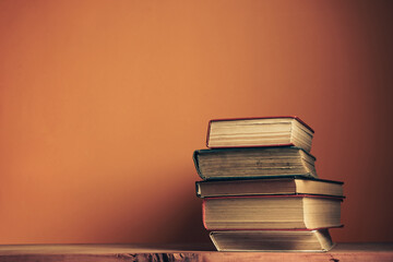 Wall Mural - Old books on a old wooden table. Beautiful orange wall background.