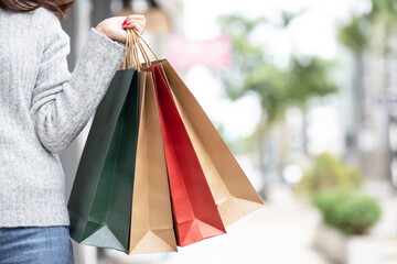 Closeup of woman hand holding shopping bag colorful paper on the street happy summer with copy space