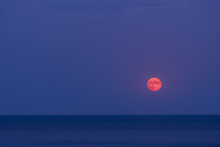 Red Full Moon In Dark Sky Above Sea In Twilight With Copy Space