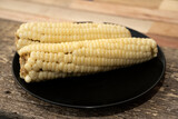 Fototapeta Tęcza - Yellow boiled corn placed on a black plate