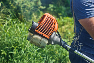 The gardener mows the grass with a lawn mower.