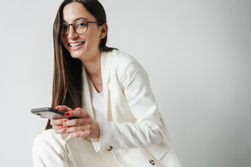 Wall Mural - Photo of laughing businesswoman in eyeglasses using mobile phone