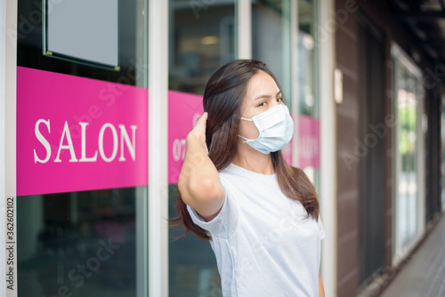 a young woman is getting a haircut in a hair salon , wearing face mask for protection covid-19 , salon safety concept
