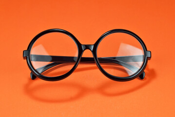 Wall Mural - Different types of glasses on an orange background close up. Glasses with round frames.