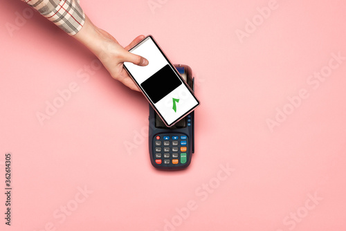 Fotomural Woman paying by phone on NFC payment contactless terminal on a pink background