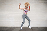 Young woman dancing with headphones and smartphone listening music - Happy multiracial woman with blond curly hair and sportswear - Emotion, technology and fitness