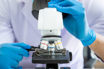 Close-up microscope with male researcher scientist medical doctor wearing coat gown using