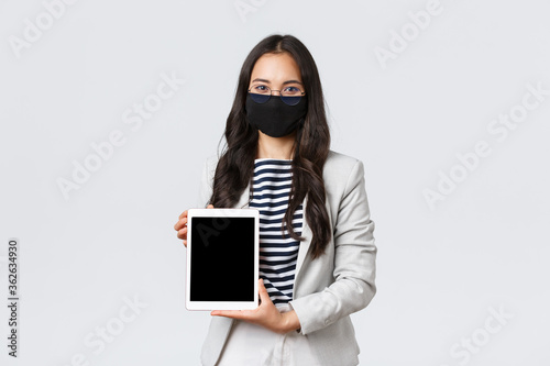 Business, finance and employment, covid-19 preventing virus and social distancing concept. Confident female real estate broker showing deal for client on digital tablet sreen, wear face mask