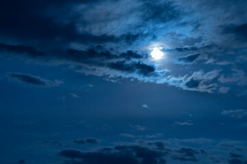 Wall Mural - Beautiful night sky. The full moon illuminates clouds.  Nature background.