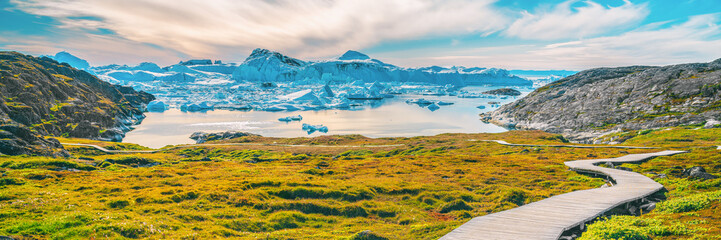 Wall Mural - hiking trail path in greenland arctic nature landscape with icebergs in ilulissat icefjord. panorami