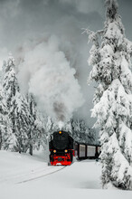 Historic Steam Train In The Winter Mountain Landscape With Snow Nature Driving To The Top Of The Brocken. Harzer Schmalspurbahn. Harz Mountains, Harz National Park In Germany.