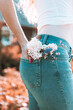 Elegant girl with flowers in the back pocket of jeans. It stands with its back to the viewer. Art photography.