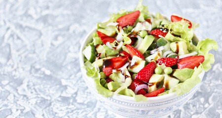 Poster - summer salad with strawberries, avocado, lettuce, onion,cucumber , green peas. dressed with balsamic sauce. copy space