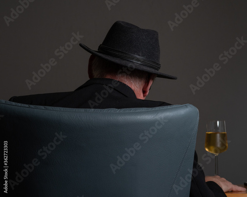 Rear View Of Man With Whiskey Sitting On Chair Against Gray Background