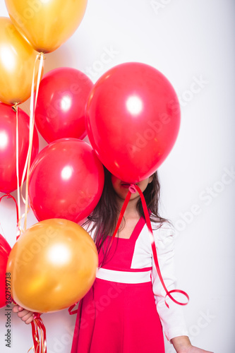Fotografía Girl With Red And Orange Balloons Standing Against White Background