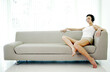 © ImageHit - Woman sitting on couch listening to music on the headphones