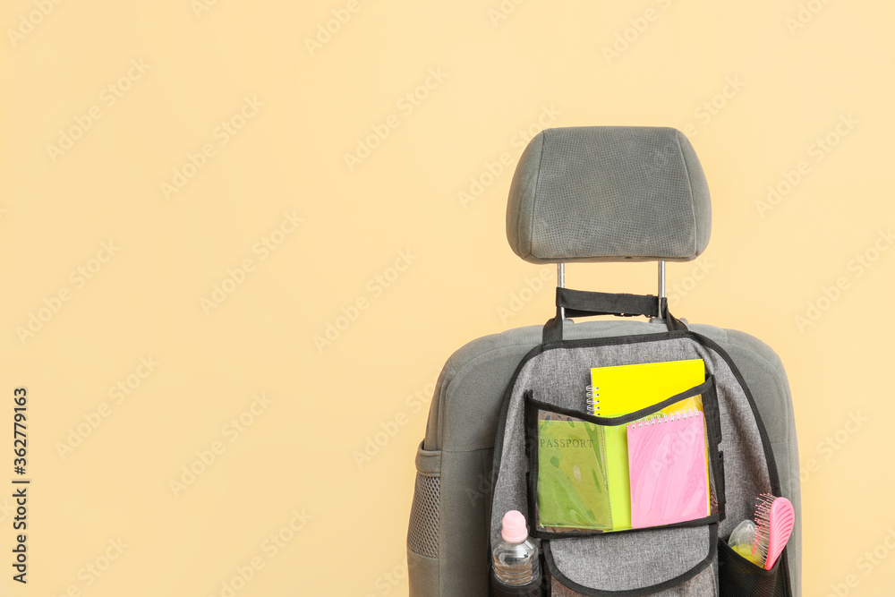 Travel organizer with different things on car seat against color background